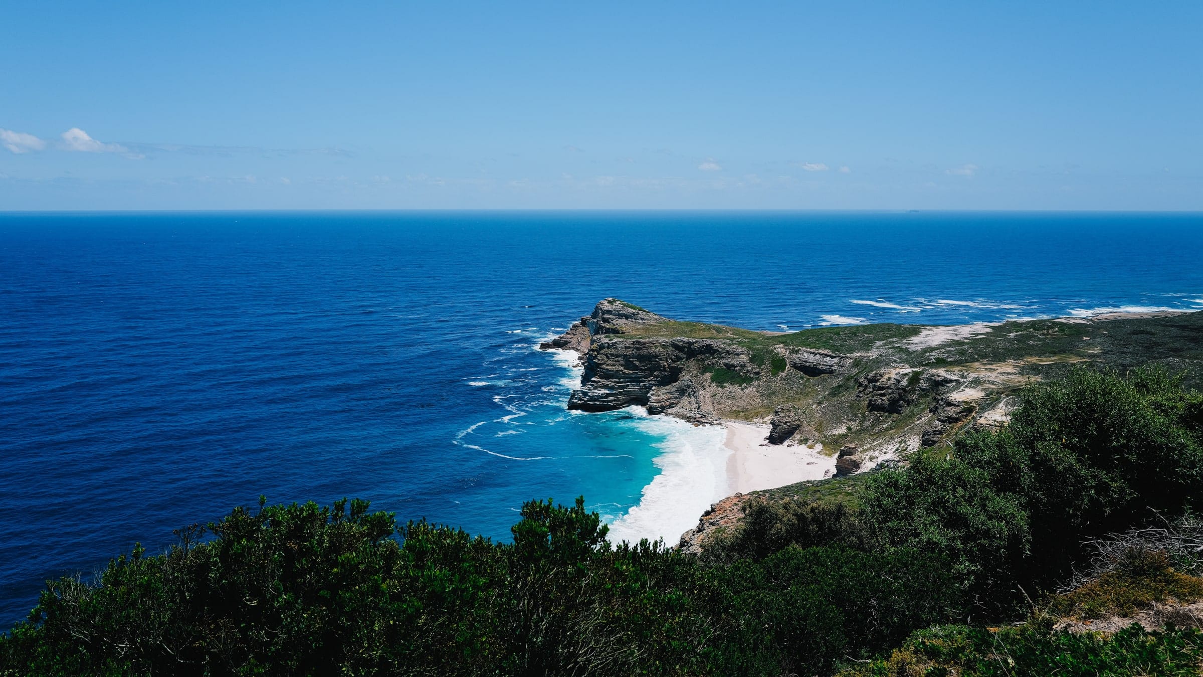 Fynbos-covered mountains dropping to the sea under a clear sky