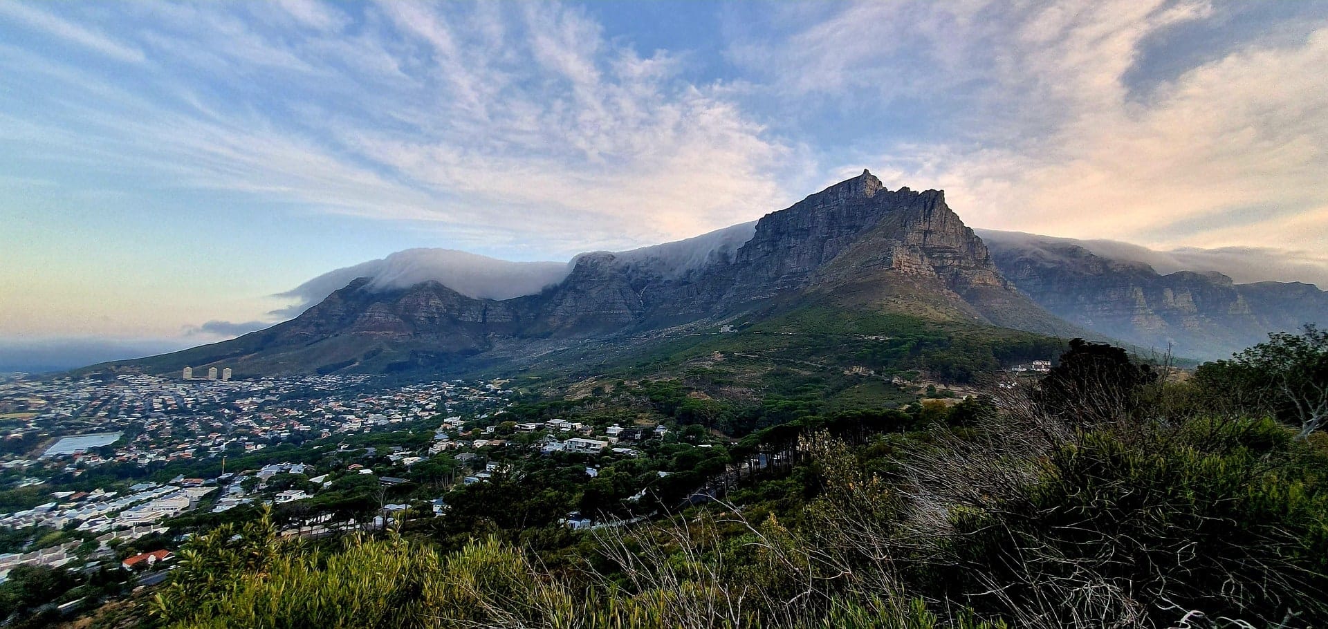Cloud pouring over the summit of Table Mountain above the city at dusk
