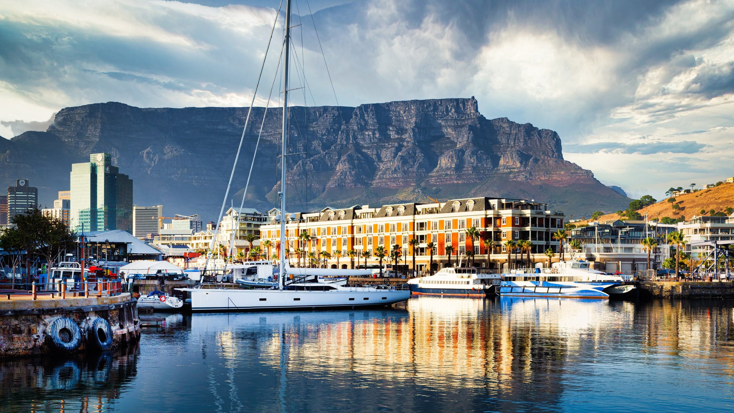 A yacht moored at the V&A Waterfront with Table Mountain rising behind the city