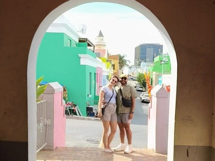 Two guests photographed through an archway on a painted street in Bo-Kaap
