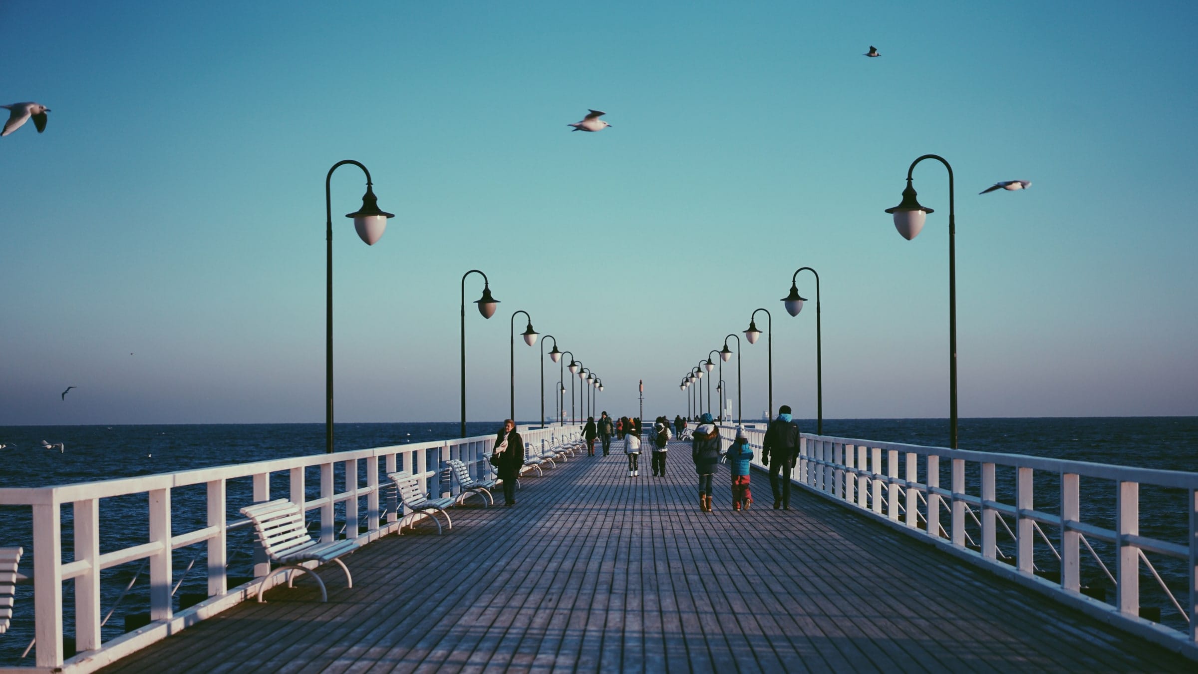 Children walking a wooden boardwalk down to a wide empty beach