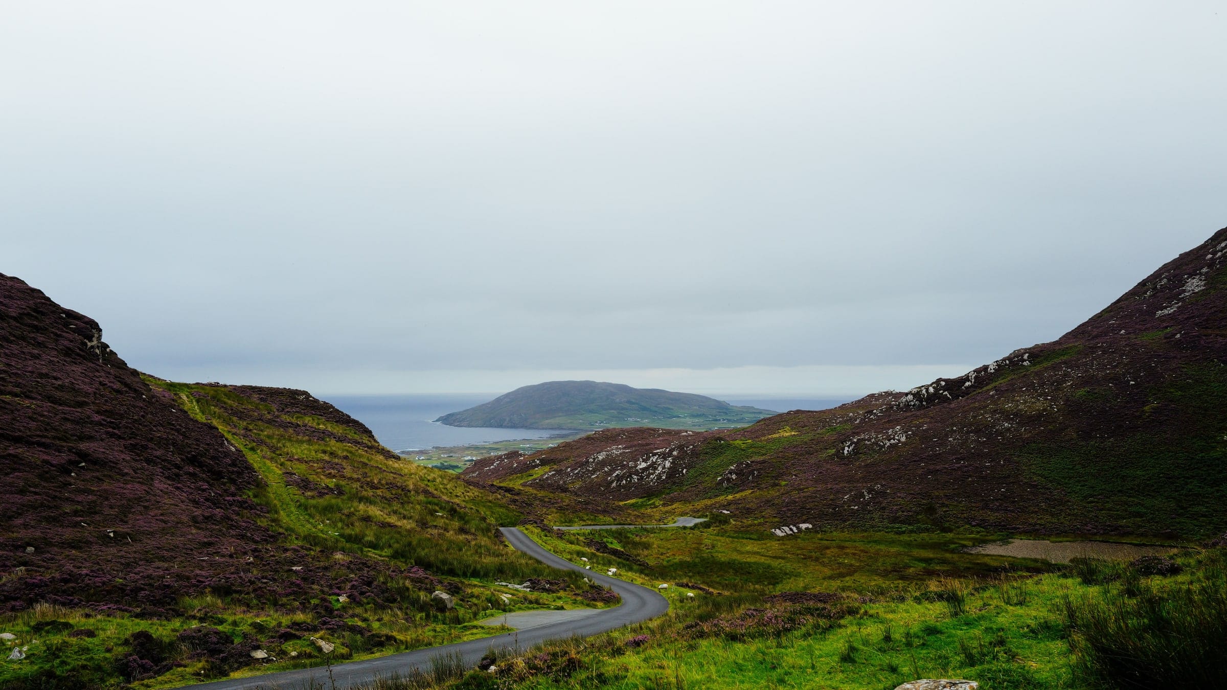 A mountain pass descending towards a distant coastline